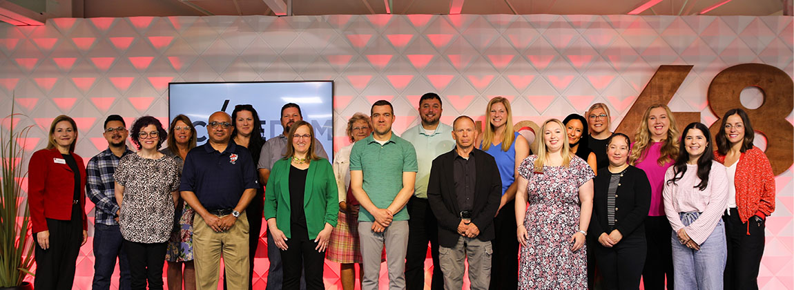 A group of people smiling in professional clothing.